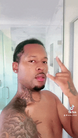 a shirtless man with a tattoo on his shoulder is giving the middle finger