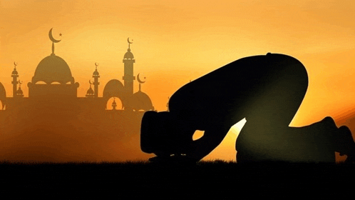 a silhouette of a man praying in front of a mosque at sunset