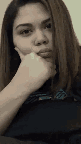a woman is covering her face with her hand and looking at the camera .