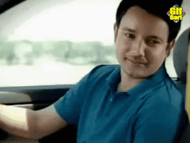 a man in a blue shirt is sitting in a car with a gif god logo on the bottom
