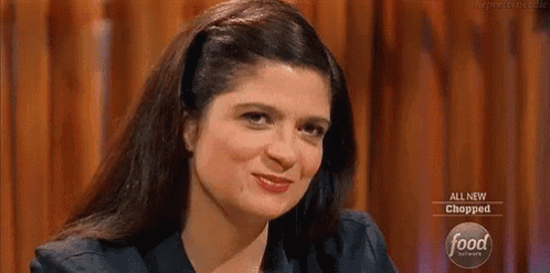 a woman is sitting at a table with a sign that says all new chopped on it .