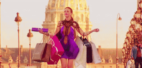 a woman in a purple dress is carrying a bunch of shopping bags on a city street .