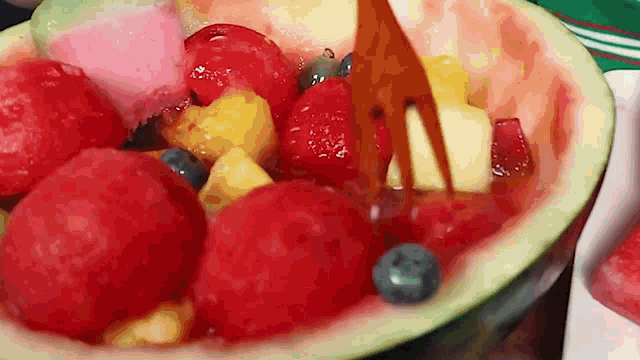 a close up of a bowl of fruit with a fork in it