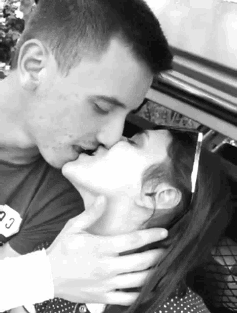 a black and white photo of a man kissing a woman on the neck