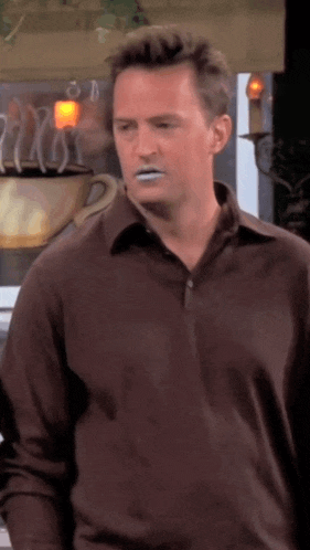 a man in a brown shirt with white paint on his face