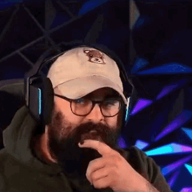 a man with a beard wearing headphones and a hat with a teddy bear on it