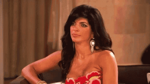 a woman in a strapless dress is sitting at a table with her hands on her hips .