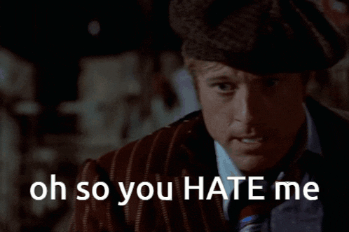 a man wearing a hat and a suit says oh so you hate me