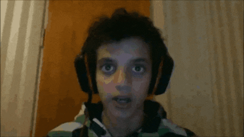 a man wearing headphones looks at the camera with his eyes closed