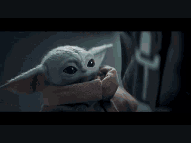 a man is holding a baby yoda in his arms in a star wars movie .