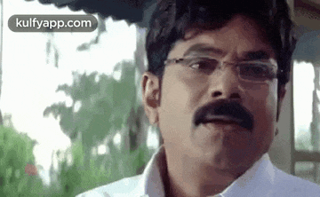 a man with glasses and a mustache is looking at the camera .