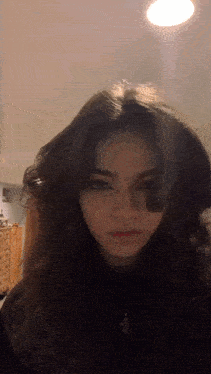 a young girl with long dark hair is taking a selfie in a room .