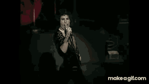 a man is singing into a microphone while standing on a stage .