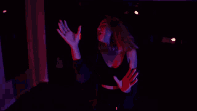 a woman singing in a dark room with purple lights behind her