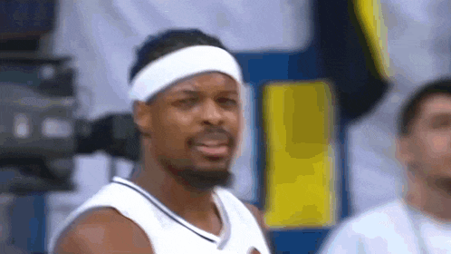 a basketball player wearing a headband and a white jersey is standing on a court .