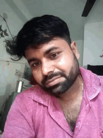 a man with a beard and a pink shirt is looking at the camera