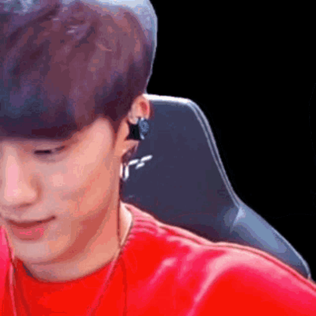 a man in a red shirt is sitting in a chair with headphones on .