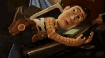 woody from toy story is laying on a table looking at his phone .