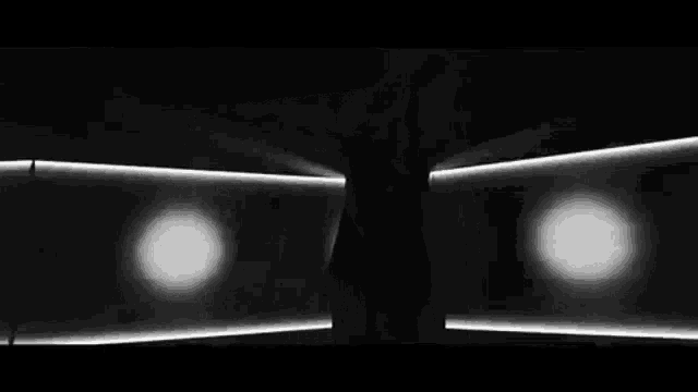 a black and white photo of a person standing in front of a wall with a lot of lights .