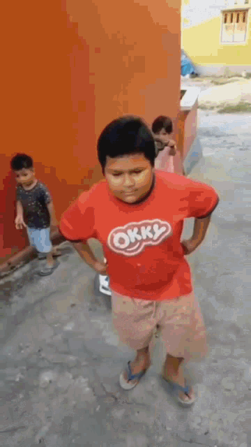 a boy wearing a red shirt that says okky on it