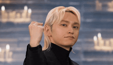 a man with blonde hair and a black turtleneck looks at the camera