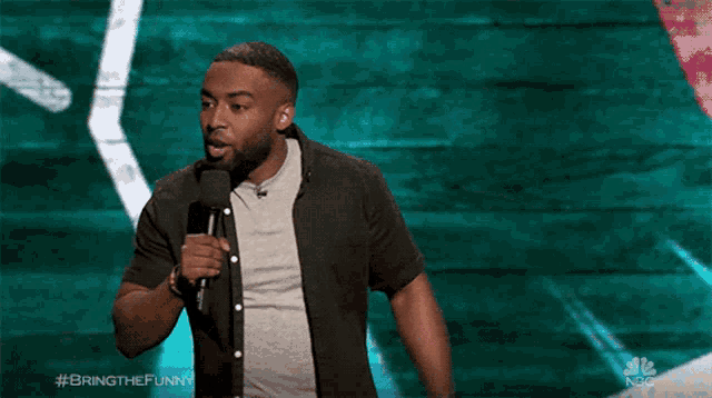 a man stands in front of a microphone with the hashtag bringthefunny