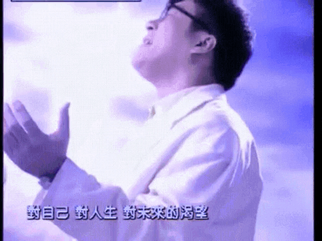 a man in a white shirt is praying with chinese writing on the screen