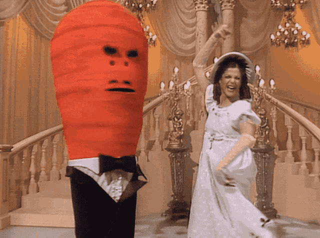 a woman in a white dress is dancing next to a man in a tuxedo with a red face
