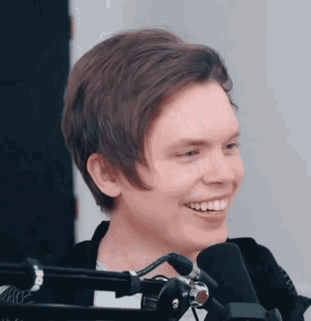 a young man is laughing in front of a microphone .