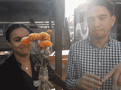 a man and a woman are standing next to each other holding flowers