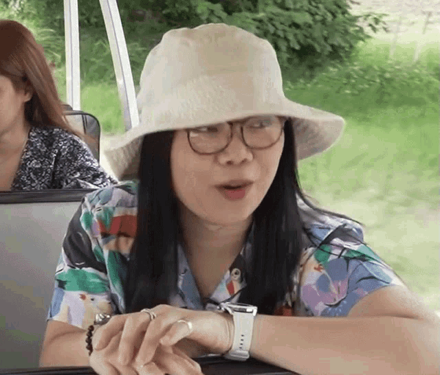 a woman wearing a hat and glasses is sitting in a car