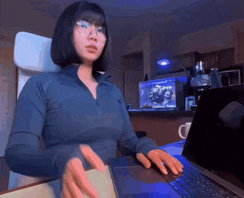 a woman wearing glasses is sitting at a desk with a laptop