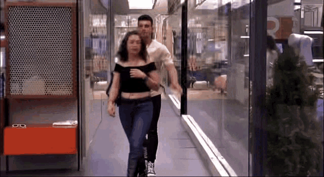 a man and a woman are walking down a hallway with the letter r on the wall