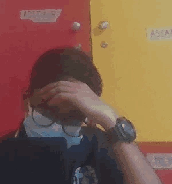 a man wearing a mask and glasses is covering his face .