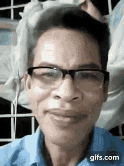 a man wearing glasses and a blue shirt is smiling at the camera .
