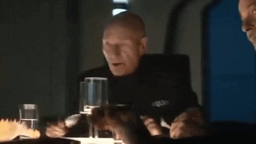 a man is sitting at a table with a glass of wine and the words `` no doubt '' written on the screen .