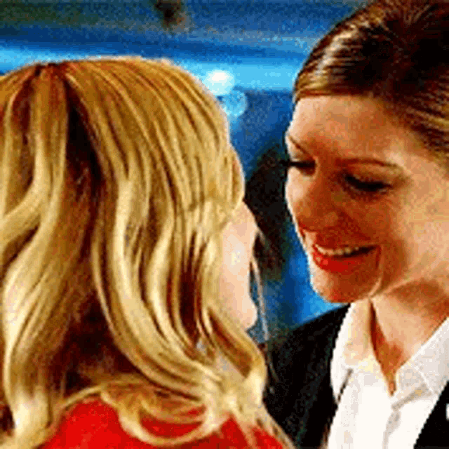 two women are smiling and looking at each other .