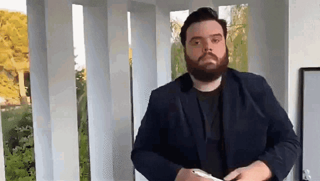 a man with a beard is wearing a black jacket and black shirt .