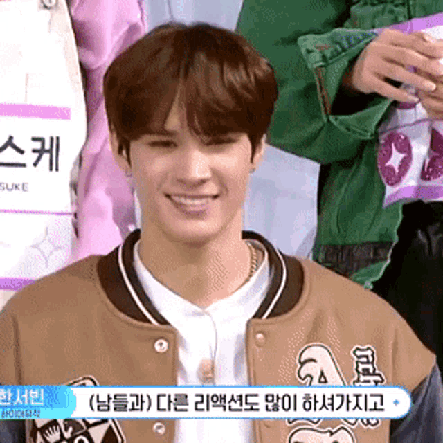 a young man wearing a brown jacket with the letter a on it smiles for the camera