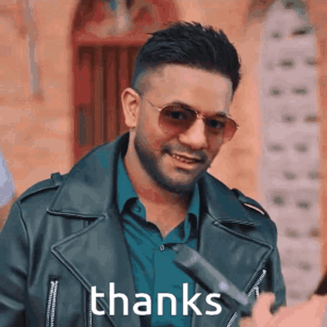 a man wearing sunglasses and a leather jacket is saying thanks .