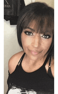 a woman wearing a black tank top and a black bra is smiling for the camera .