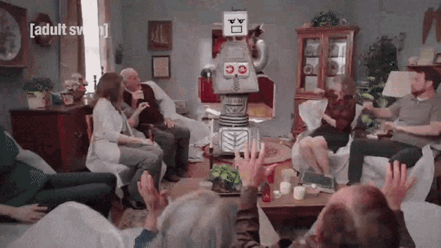 a group of people are sitting around a table in a living room with a robot in the middle .