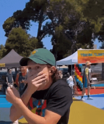 a man wearing a green hat is covering his face in front of a yellow sign that says ' bus ' on it