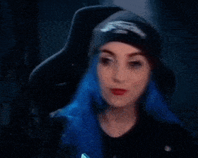 a woman with blue hair is wearing a black hat and a black shirt .