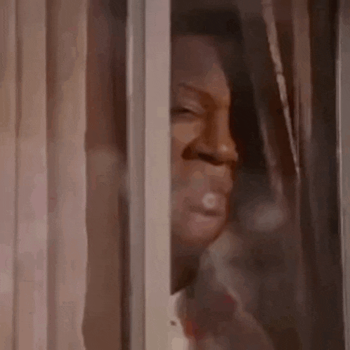 a man is looking out of a window with his eyes closed .