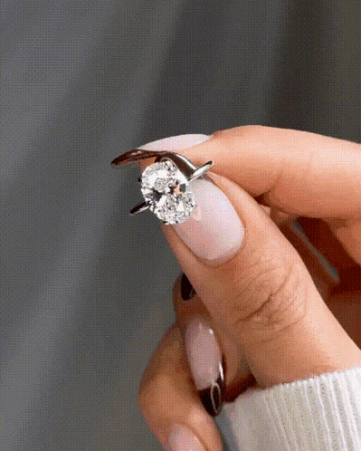 a woman 's hand is holding a diamond ring on her finger