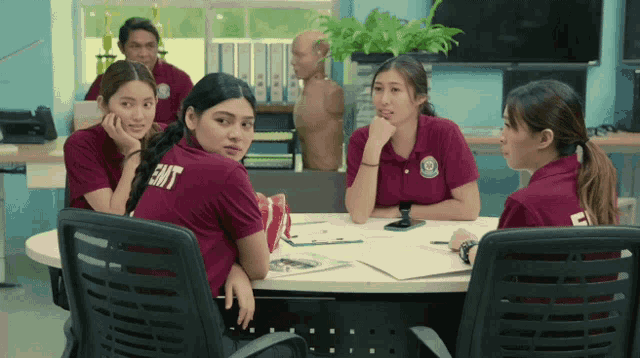 a group of women are sitting around a table and one of them has the word emt on her shirt