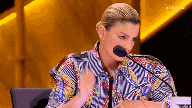 a woman in a colorful shirt is speaking into a microphone