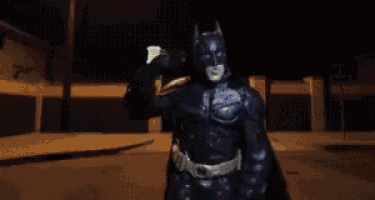a man in a batman costume is holding a light in his hand .