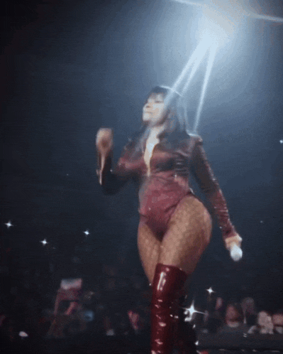 a woman in a red bodysuit and red boots holds a microphone